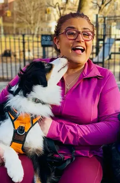 imgi_3_HHH_contact_PIC_C Professional dog walker on bench with dog who is licking her face.